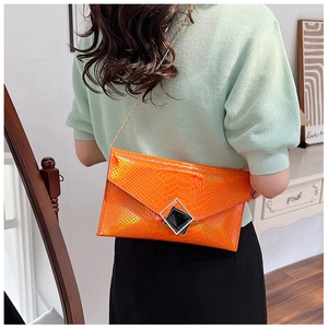 Dettaglio di una borsa a mano arancione pitonata con catena dorata e fibbia geometrica