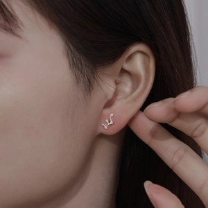 Close-up of a silver zodiac stud earring with sparkling cubic zirconia on a model ear