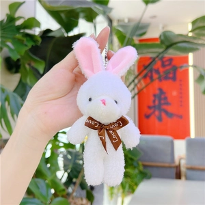 Gros plan d'un porte-clés lapin en peluche blanc avec oreilles roses et un nœud
