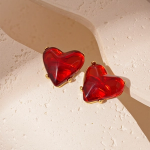 Macro shot of 3D red heart earrings with high-gloss glass finish and gold prong settings