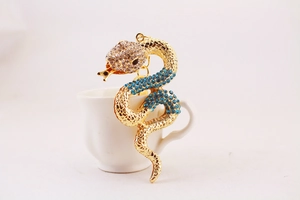 Close-up of golden snake keychain featuring clear and blue rhinestones on metal