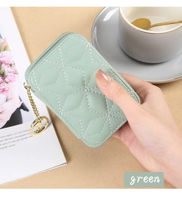 Detail of mint green quilted mini cosmetic bag with gold chain and mirror accessory