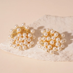 French vintage cluster pearl stud earrings with gold base on a white stone background