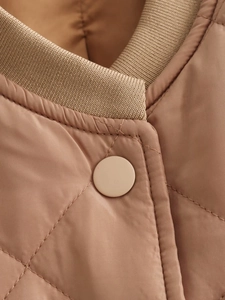 Detailed close-up of quilted bomber jacket collar with rib-knit trim and matching button