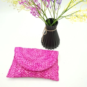 Pochette a busta color fucsia in paglia intrecciata a mano con decoro floreale