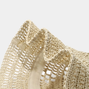 Detailed macro view of beige straw hat featuring delicate hollow weave patterns and texture
