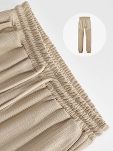 Detailed close-up of khaki waffle texture fabric and drawstring waistband on men's trousers