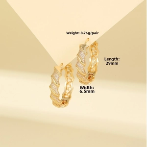 Macro detail of twisted gold hoop earrings with white zircon, 29mm length and 8.76g weight
