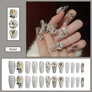 Macro detail of luxury silver glitter press-on nails with rhinestones and pearls