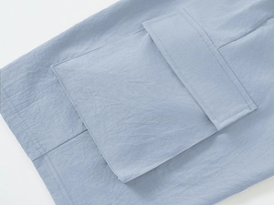 Detail of light blue cargo shorts featuring a functional pocket and woven fabric texture