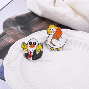Detail of two cartoon duck enamel pins with agent and bread motifs on a white plate