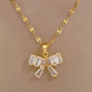Macro shot of gold bow pendant with rectangular zircons on flat knotted chain
