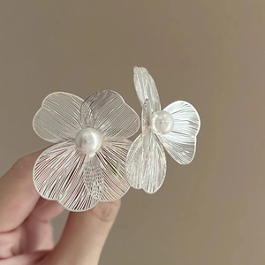 Detailed macro view of silver flower earrings with delicate metal mesh and central pearl