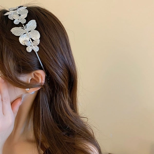 Detail of silver butterfly headband featuring embossed textures on a thin metal band