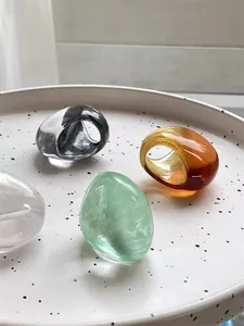 Detail of colorful chunky resin rings in amber, smoky grey and green on a ceramic tray