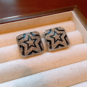Macro detail of vintage square earrings with crystal star pattern on black enamel