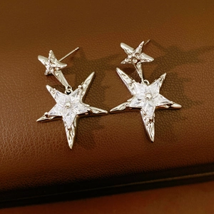 Makroaufnahme von Stern-Ohrhängern aus Silber mit klaren Zirkonia auf Leder