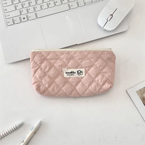 Pink quilted rhombic makeup bag shown on a desk with a laptop and stationery