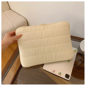 Detailed close-up of quilted cream laptop sleeve with soft padded shockproof texture