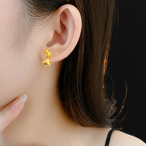 Gros plan d'un mannequin portant une boucle d'oreille koi dorée au lustre métallique