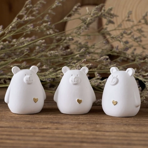 Three minimalist white bear sculptures with gold hearts on a rustic wooden table