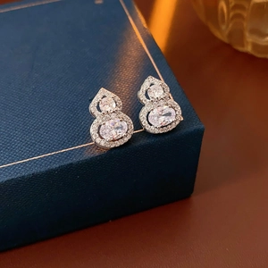 Silver-finish gourd earrings with cubic zirconia inlay on a blue velvet jewelry box