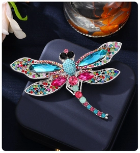 Detailed view of luxury dragonfly brooch with colorful crystals on blue leather