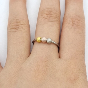 Detail of movable matte beads in gold, rose gold and silver on an adjustable ring band