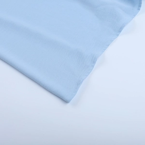 Détail de la texture du tissu bleu clair scintillant et de l'ourlet de la robe trapèze