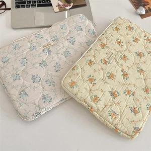 Detail of floral quilted cotton laptop sleeves with embroidery and dual zippers