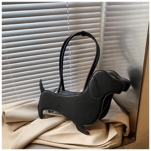 Detailed view of dachshund-shaped black shoulder bag on a beige blazer background