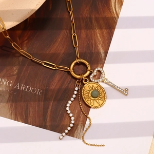 Detail of 18K gold plated necklace with sun medallion and heart key charms on a magazine
