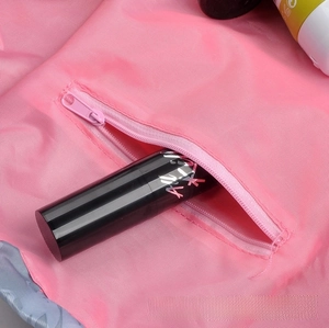 Detail view of the pink drawstring makeup bag showing a zipper side pocket for lipsticks