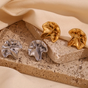 Detailed view of gold and silver irregular hammered metal earrings on a textured stone base