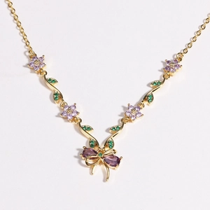 Makroaufnahme der goldenen Blumenhalskette mit lila Kristallblume und Schleife