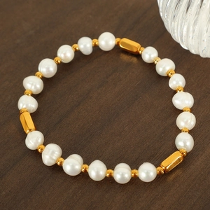 Elegant freshwater pearl bracelet with gold metal tubes on a dark wooden surface