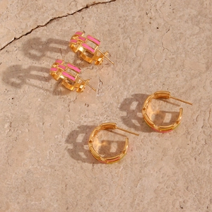 Golden 18K plated C-shaped earrings with pink enamel inlay on natural stone surface