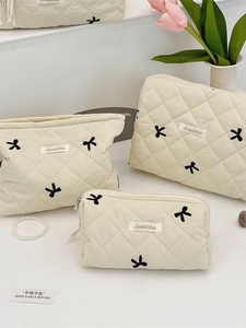Three-piece cream quilted cosmetic bag set with embroidered bows and Soraakka label