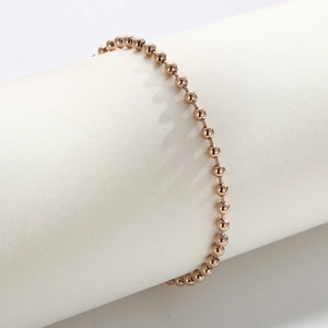 Detail of rose gold beaded ball chain bracelet wrapped on a white cylindrical stand
