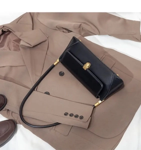 Detailed close-up of a black leather rectangular baguette bag with a golden metal buckle
