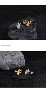 Detailed view of two-tone pear-shaped zircon rings on dark textured stones with elegant light