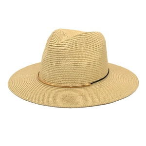Close-up of beige straw fedora featuring a black ribbon and gold metal accent detail