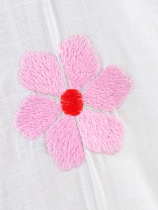 Macro detail of pink flower embroidery on white cotton linen long-sleeved shirt fabric
