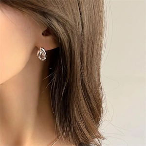 Close-up of elegant S925 sterling silver twisted knot hoop earrings worn by a model