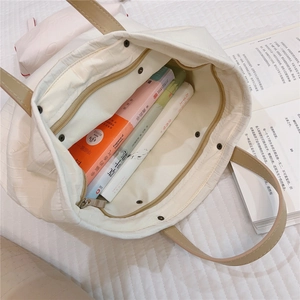 Detail view of large white tote bag with crocodile pattern and interior zip pocket