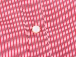 Detail of red and white striped fabric featuring a polished gold-rimmed button