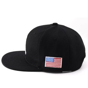 Detail of black snapback cap featuring an American flag embroidered patch on the side