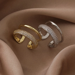 Detail of double-layer open ring featuring paved zircons and smooth metallic finish