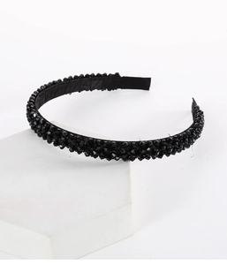 Close-up of black beaded headband with faceted crystals on a minimalist display