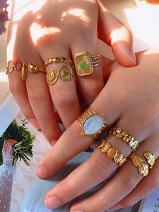 Close-up of stacked vintage gold rings with green malachite and bohemian heart details